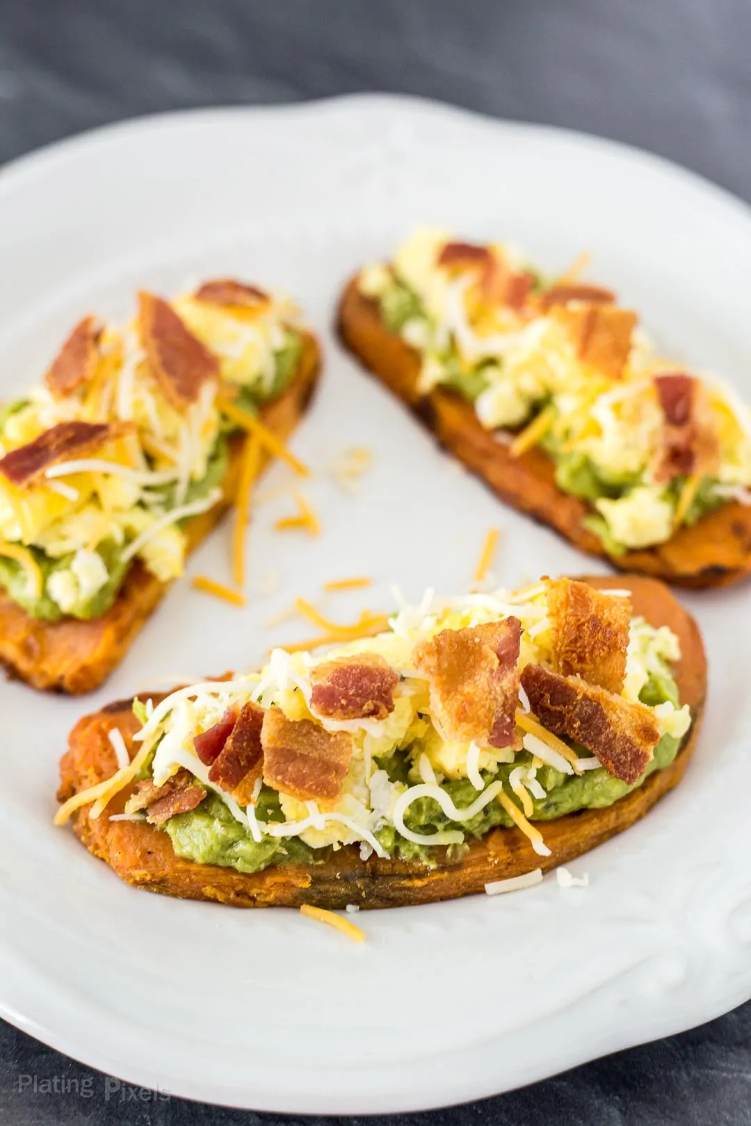 Three prepared Bacon and Egg Sweet Potato Bites on a plate