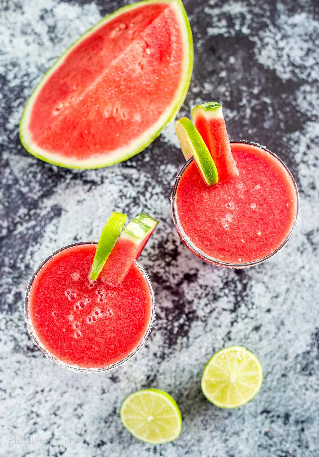 Overhead shot of two Frozen Watermelon Margarita next to a watermelon wedge