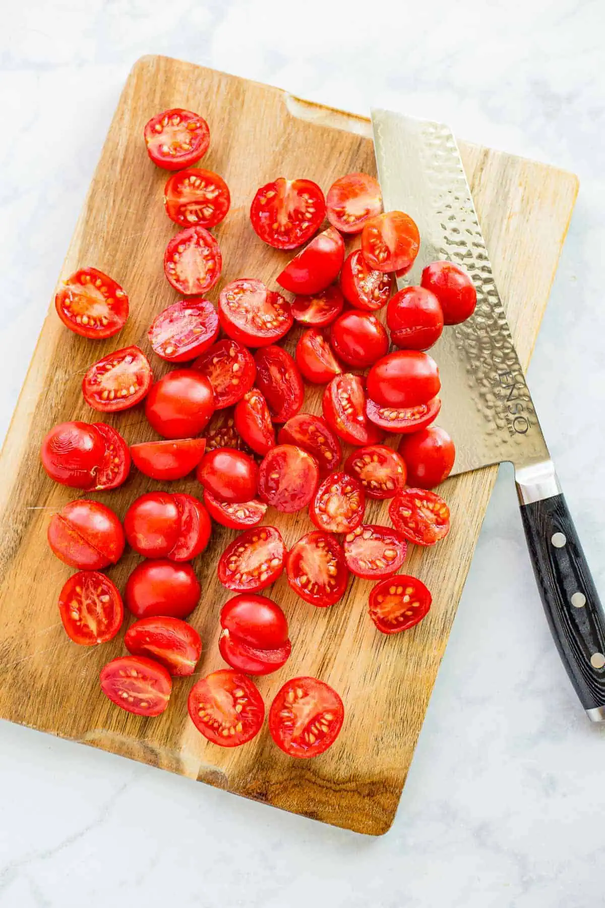 Halved fresh cherry tomatoes on a cutting board