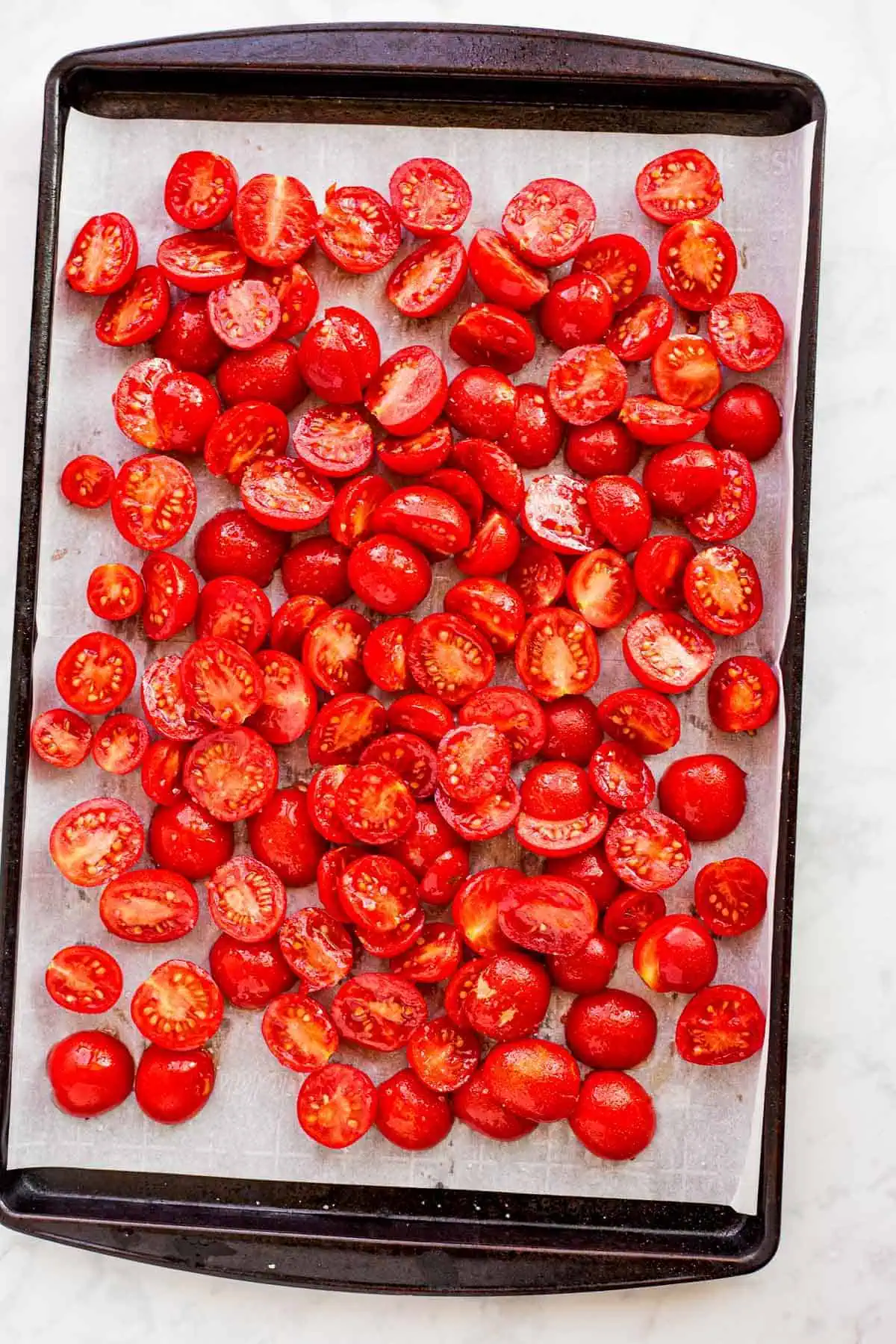 Halved cherry tomatoes on a baking sheet