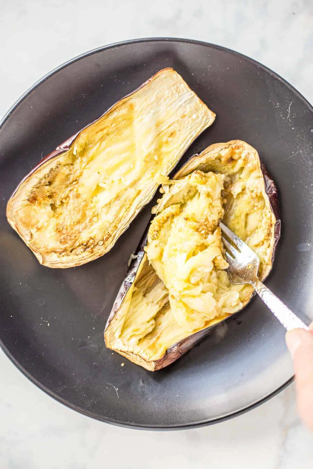 Scooping out the inside of a roasted eggplant