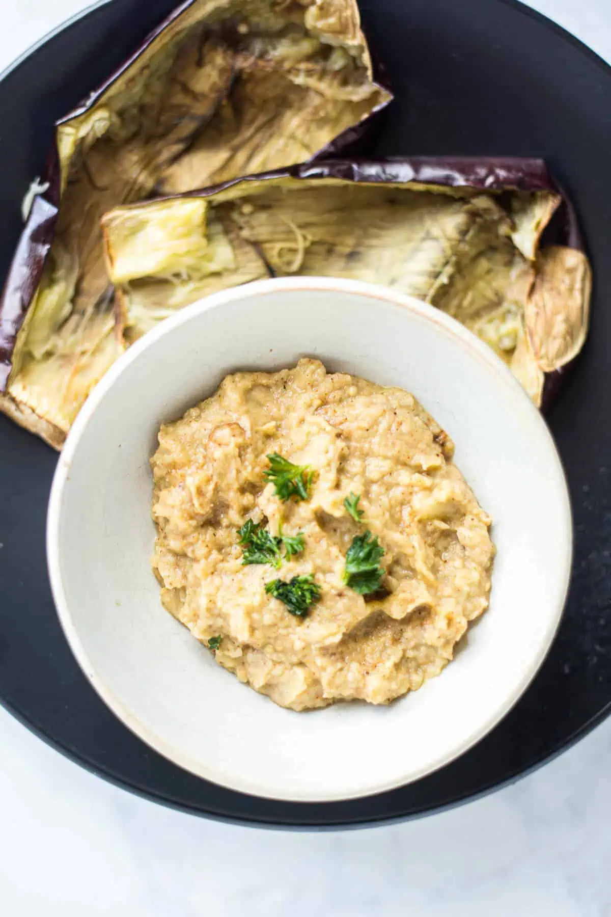 Eggplant dip in a white bowl next to air fried eggplant