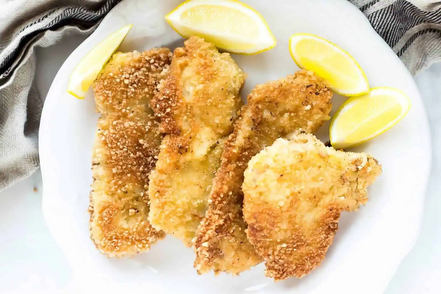 Pork Schnitzel on a plate garnished with lemons landscape format