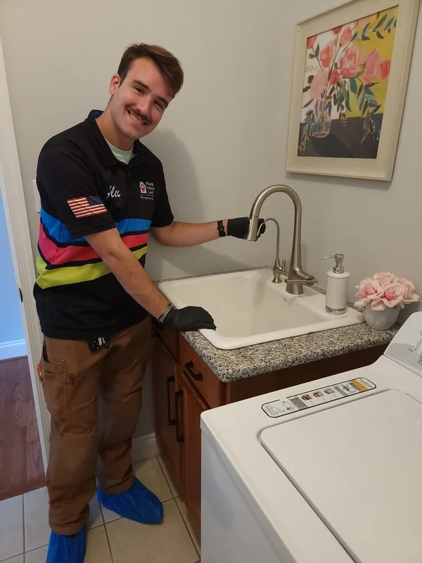 A man stands by a kitchen counter using a prosthetic arm to pour water from a kettle into a French press.
