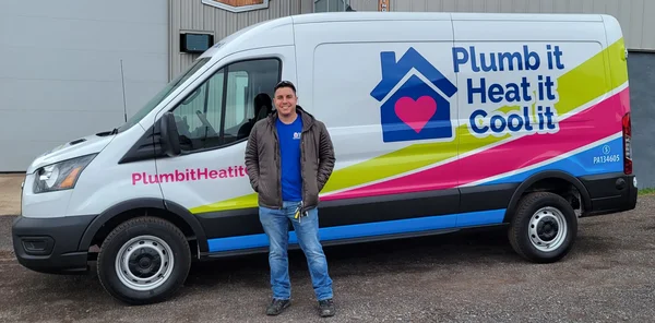 A man stands in front of a white service van with colorful graphics and the text "Plumb it Heat it Cool it" on the side.