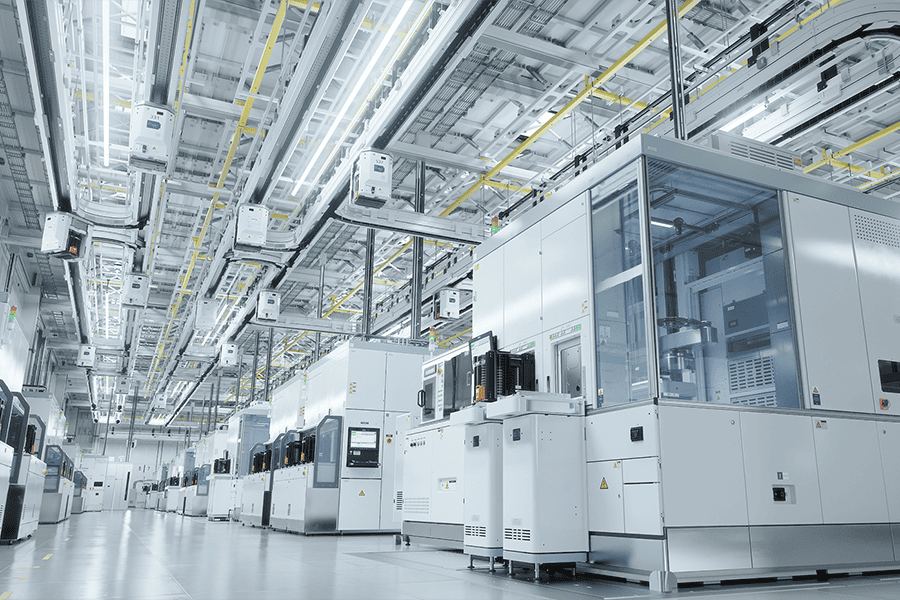 Large clean, high-tech industrial facility floor with rows of automated production machines and equipment under bright overhead lighting.