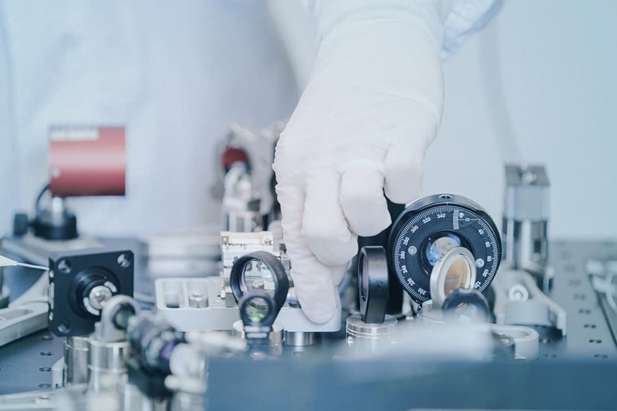 Engineer monitoring air contamination levels using a portable Lasair Pro particle counter in a cleanroom.
