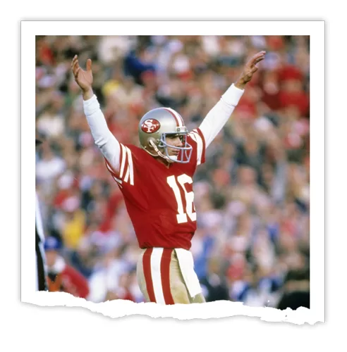 Joe Montana, wearing a red and gold uniform, raises his arms in celebration during a football game.