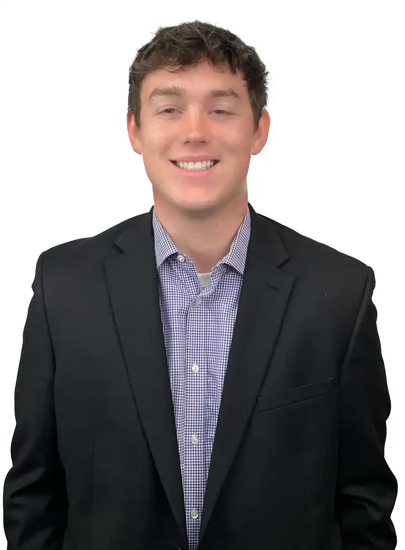 Logan O'Brien in a black suit and checkered shirt, smiling against a white background.