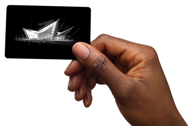 A hand holding a black card featuring a white ink design of a modern building.