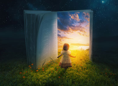 A child standing in front of an open book with a sunset scene emerging from its pages.