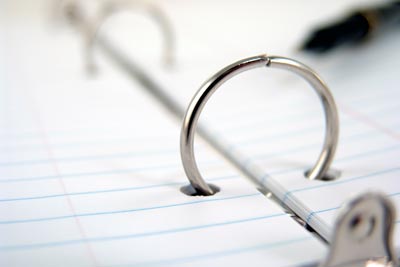 Closeup view of a 3-ring binder with metal rings and lined paper.