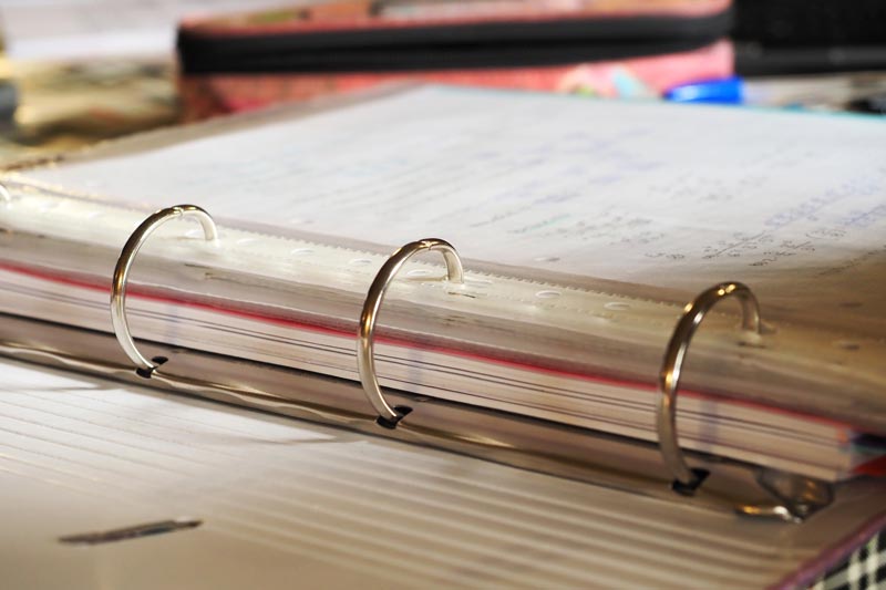 Close-up of a custom 3-ring binder with visible rings and pages inside.
