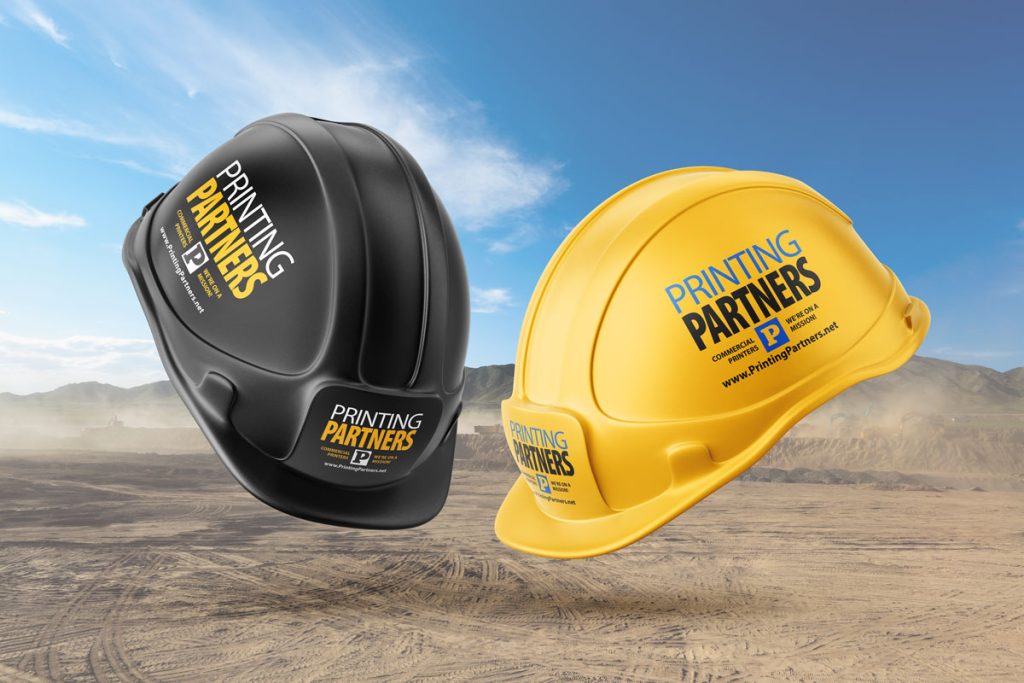 Black and yellow custom printed hard hats featuring the Printing Partners logo.