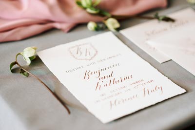 Foil stamped wedding invitation featuring elegant typography and floral accents on a textured surface.