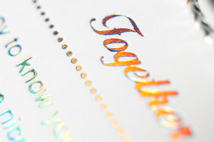 Close-up of a foil stamped flyer featuring iridescent text that reads 'Together'.