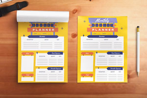 Two full-color custom notepads featuring a monthly planner layout on a wooden surface.