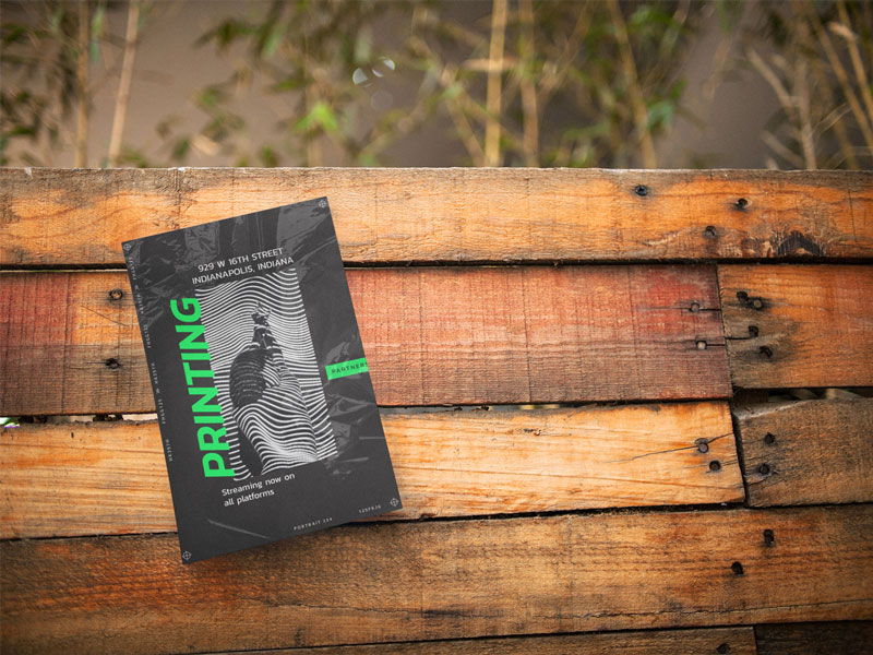 Half-size flyer with a black and green design placed on a wooden surface.