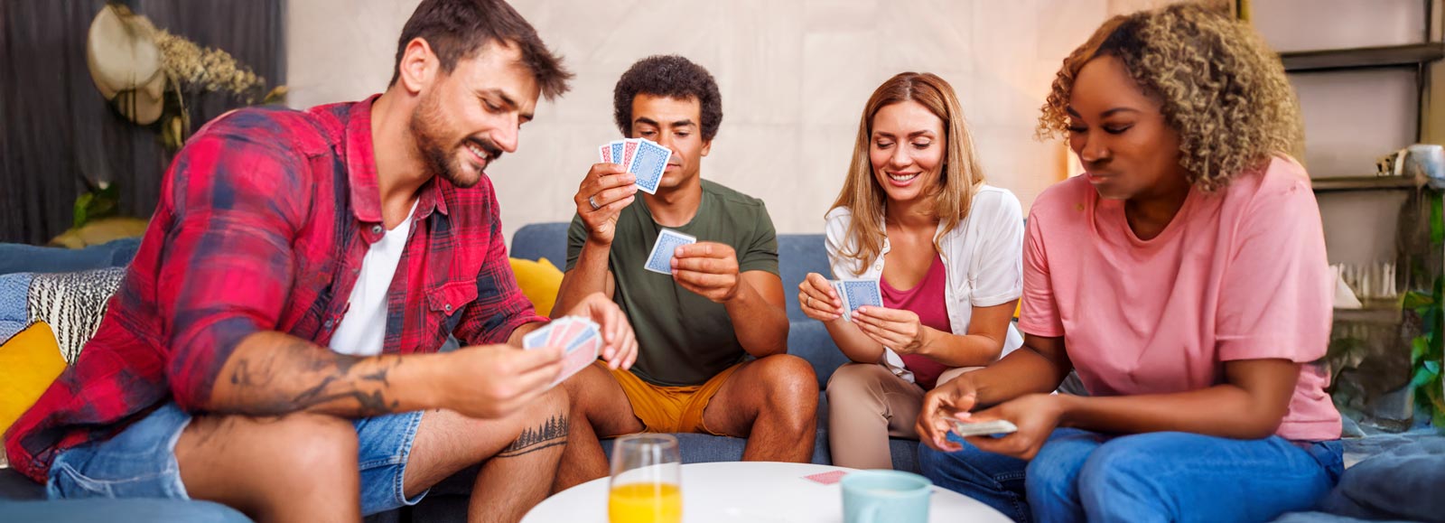 Four friends sitting around a table playing cards together in a casual setting.