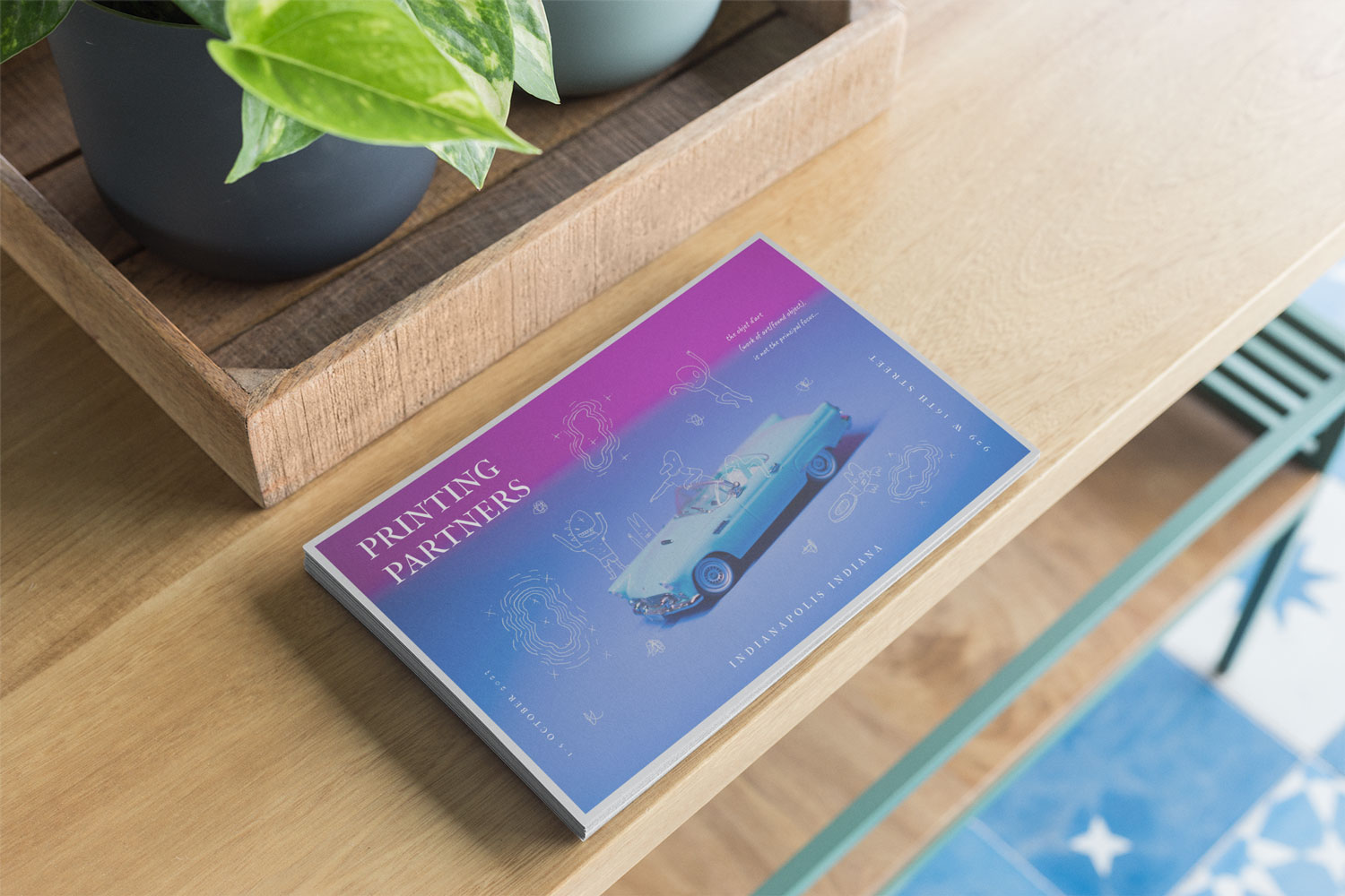 A postcard featuring a blue gradient design with illustrations and the text 'Printing Partners' on a wooden table.