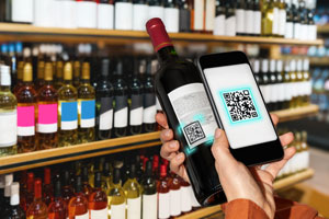 A person holding a smartphone scanning a QR code on a wine bottle in a store.