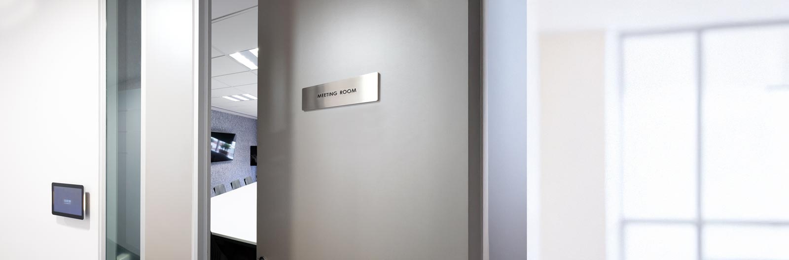 A sign labeled 'Meeting Room' on a door with a modern design.