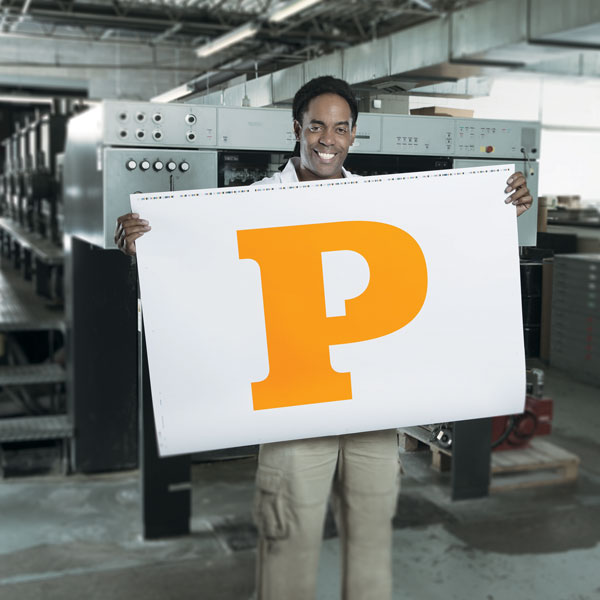 Baron Vaughn holding a large print of the letter P in orange color.
