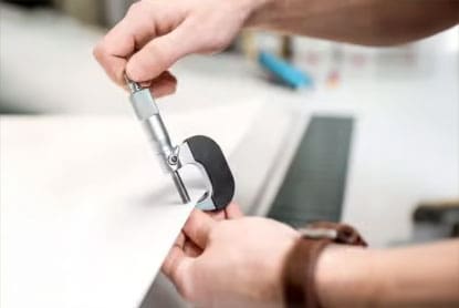 Micrometer measuring the thickness of a paper sheet in a printing plant setting.