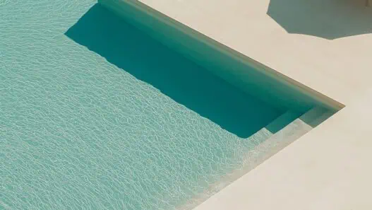 a pool with lounge chairs and a step