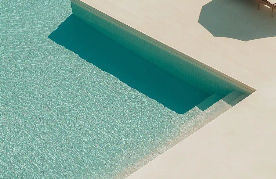 a pool with lounge chairs and a step
