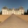 a large white building with a path leading to it with Château de Cheverny in the background