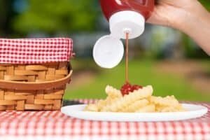 Creamy mashed potatoes topped with cherry sauce, served outdoors with a picnic basket and red checkered tablecloth. Perfect for outdoor dining, showcasing delicious comfort food.