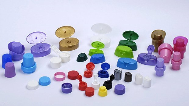 Colourful plastic caps and lids in various sizes and shapes on a white background.