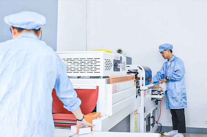 High-tech manufacturing facility with engineers operating advanced printing and packaging machinery in a clean, professional industrial environment.