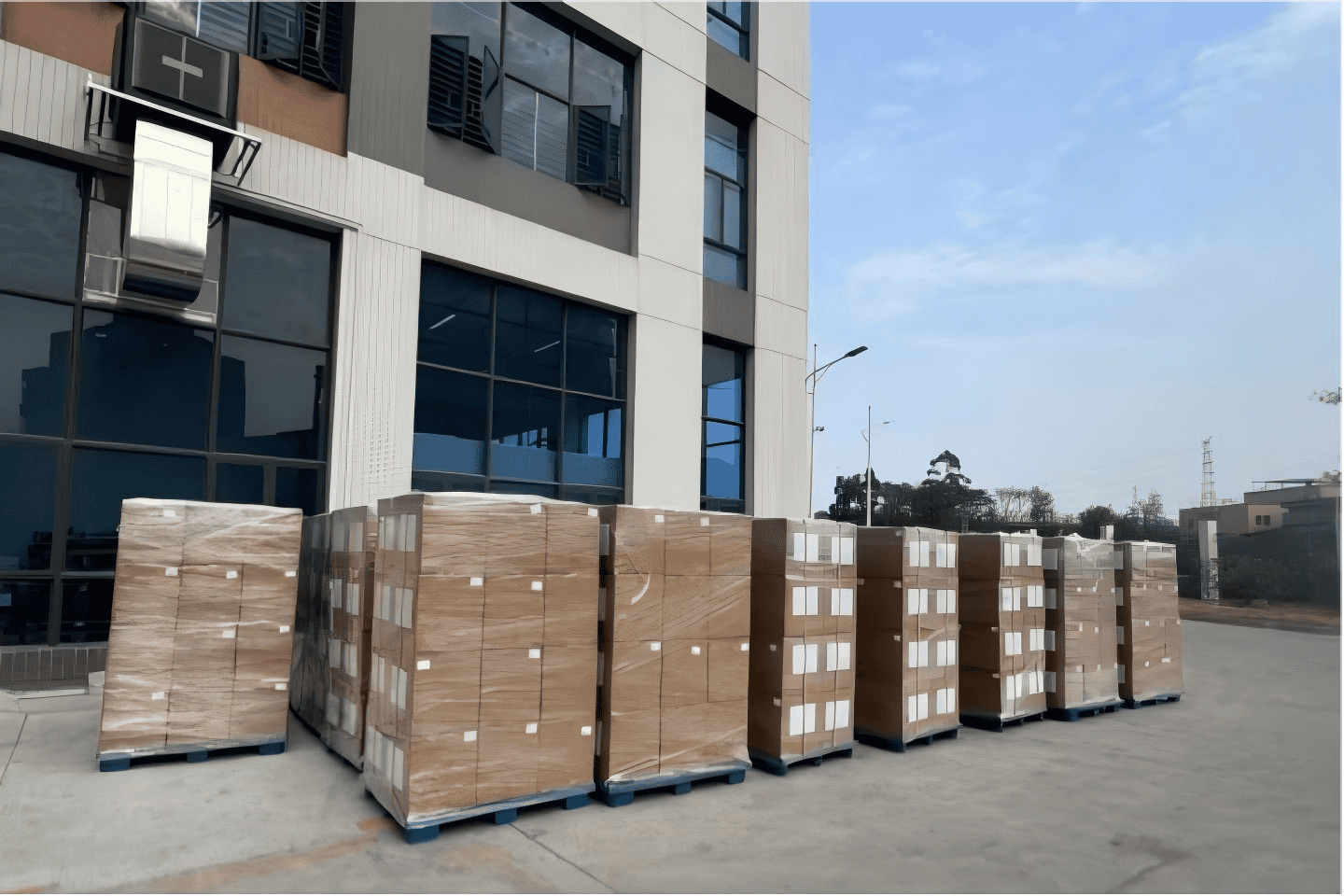 Pallets of packaged goods ready for distribution outside a commercial building, showcasing logistics and supply chain operations.