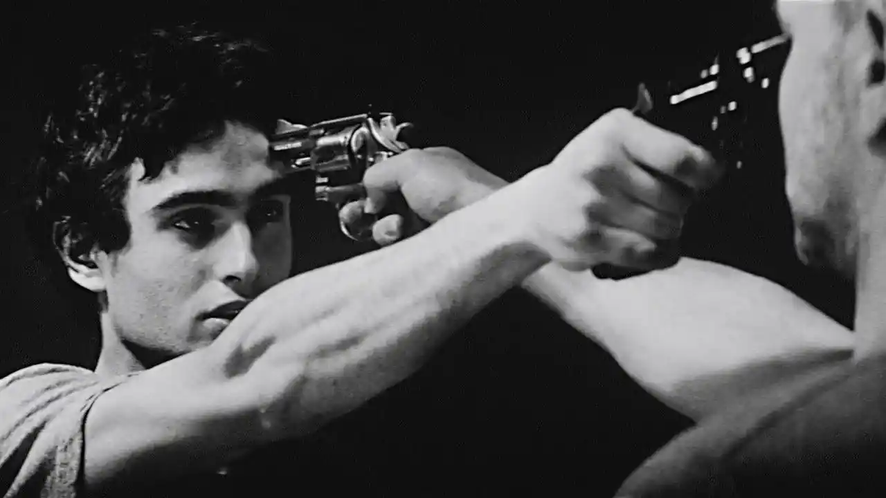 Disparo en una escena de película clásica, tensión y drama en blanco y negro, protagonista joven con expresión intensa, enfrentamiento con arma de fuego, estilo cinematográfico de cine negro.