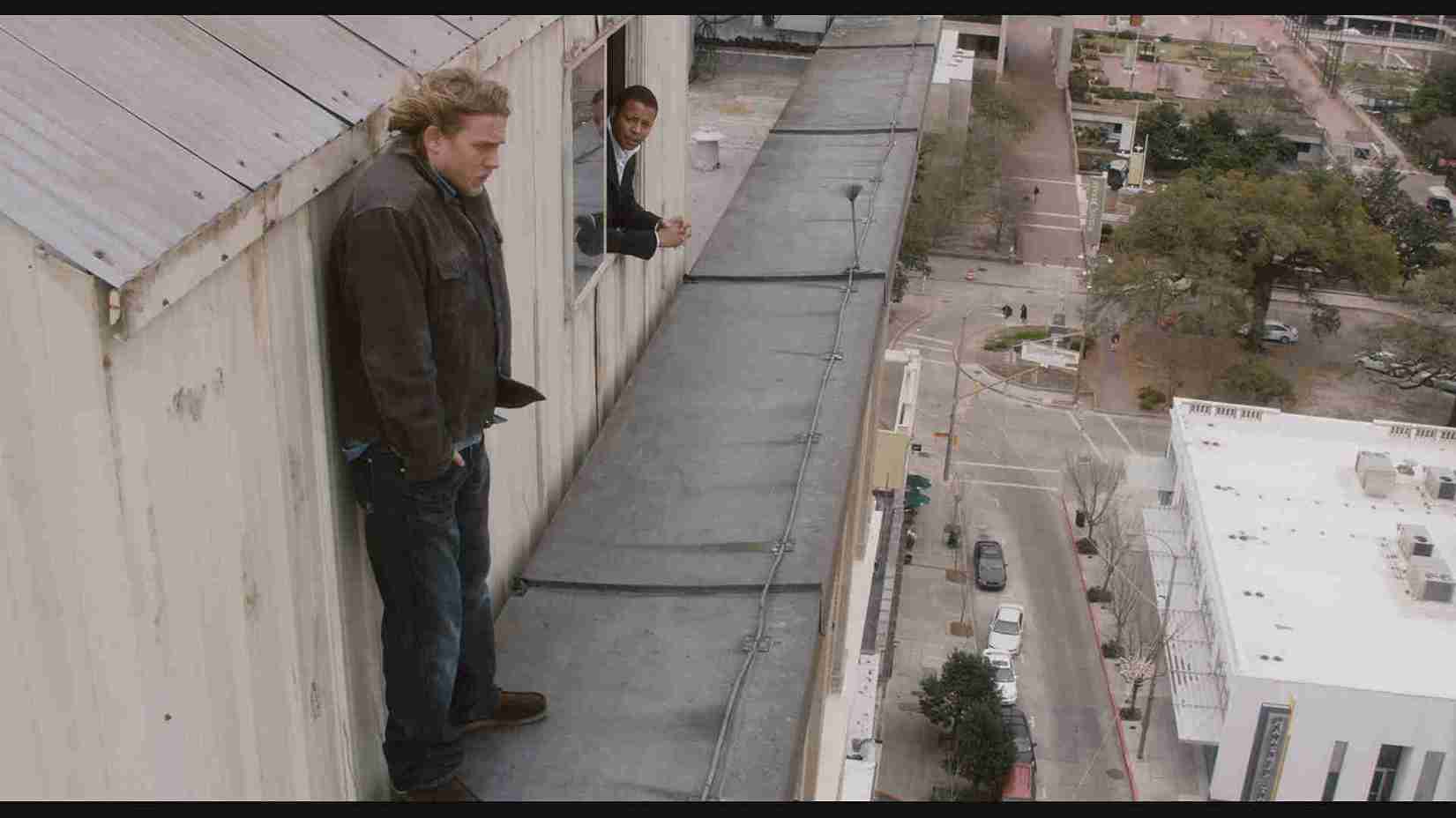 Búsqueda de la mejor película para ver: escenas desde un edificio alto mostrando dos hombres, uno en un balcón y otro en una ventana, con vista a la ciudad, en un entorno urbano y moderno.