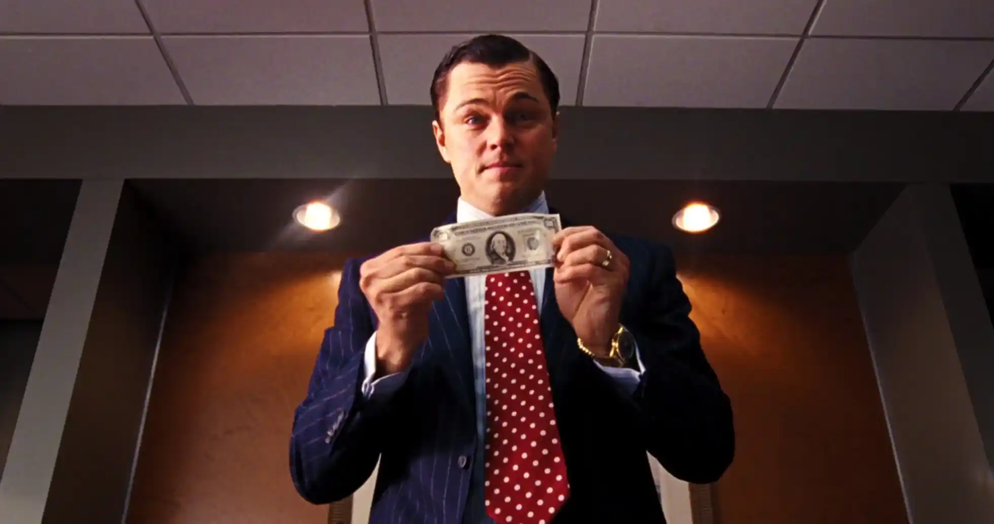 Dinero en mano, personaje de la película "El Lobo de Wall Street", mostrando éxito financiero y codicia.
