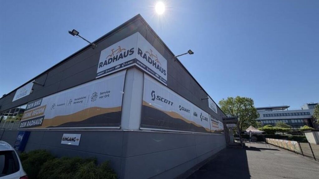 Gewerbegebäude mit Radhaus- und Scott-Werbepanels bei Sonnenlicht.
