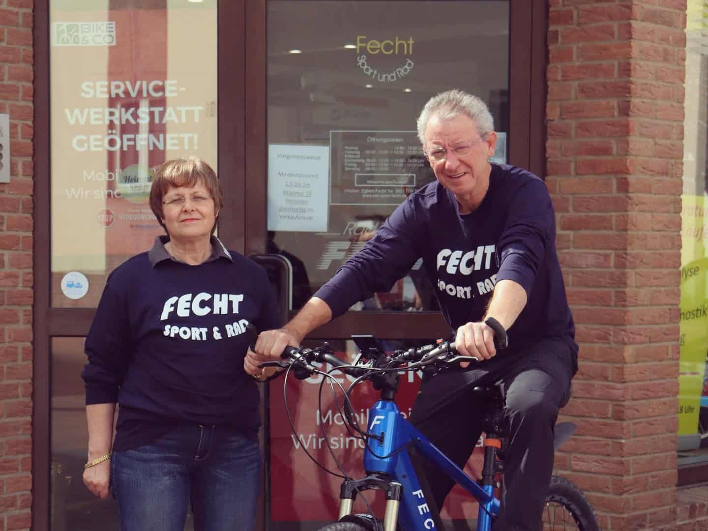 Zwei Mitarbeiter von Radsport Fecht mit Fahrrad vor Geschäft.