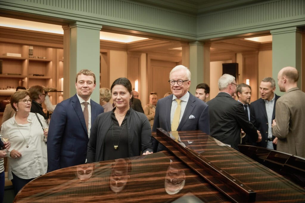 Elegant man and woman at a formal social event with a grand piano in the foreground.