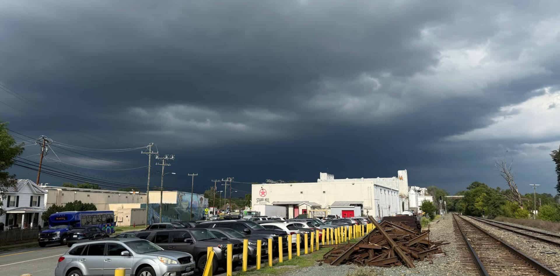 Dark storm clouds over a parking lot and train tracks in a small town.