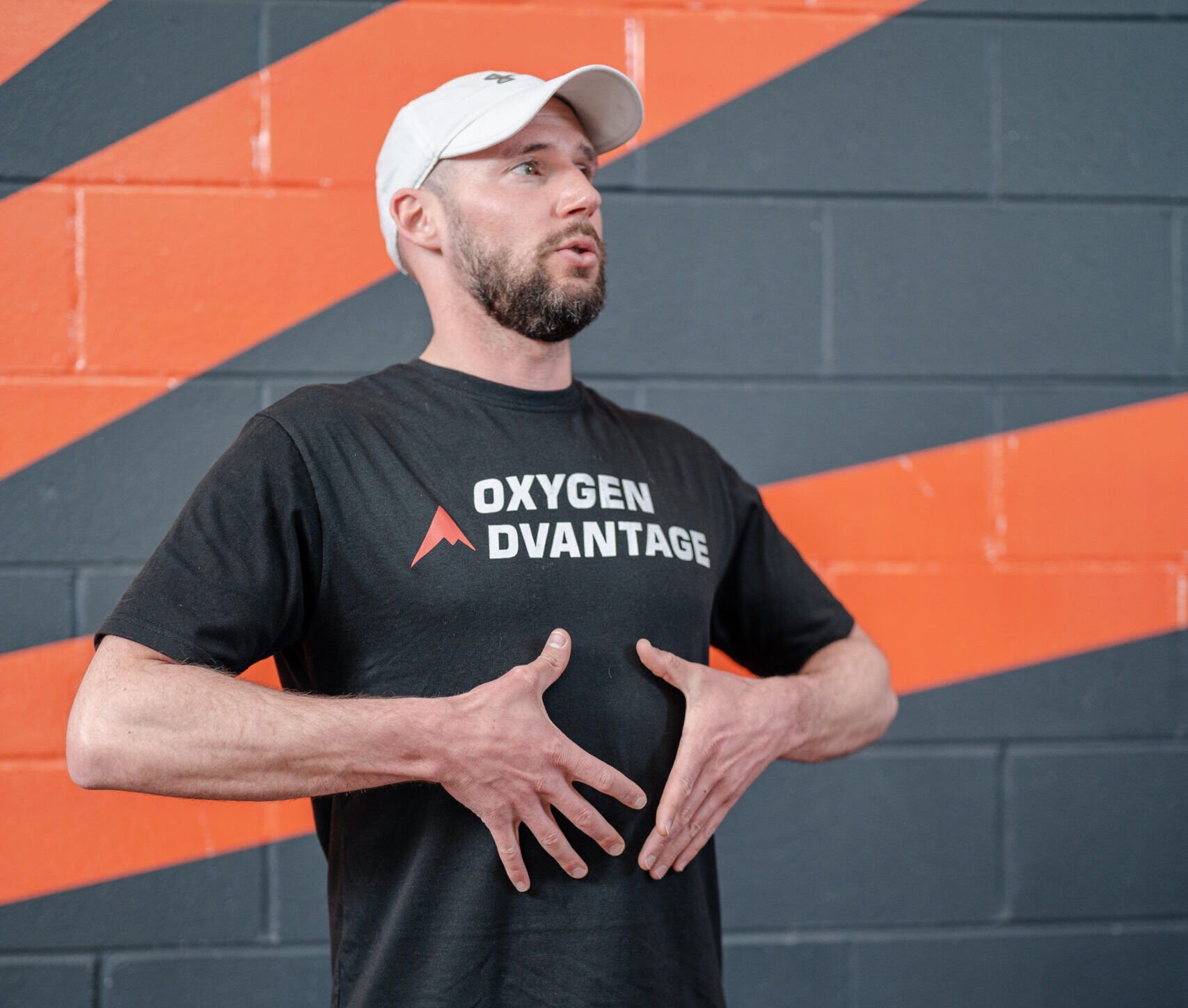 Man leading a breathwork training session with his hands near his diaphragm, showing the class how to breathe.