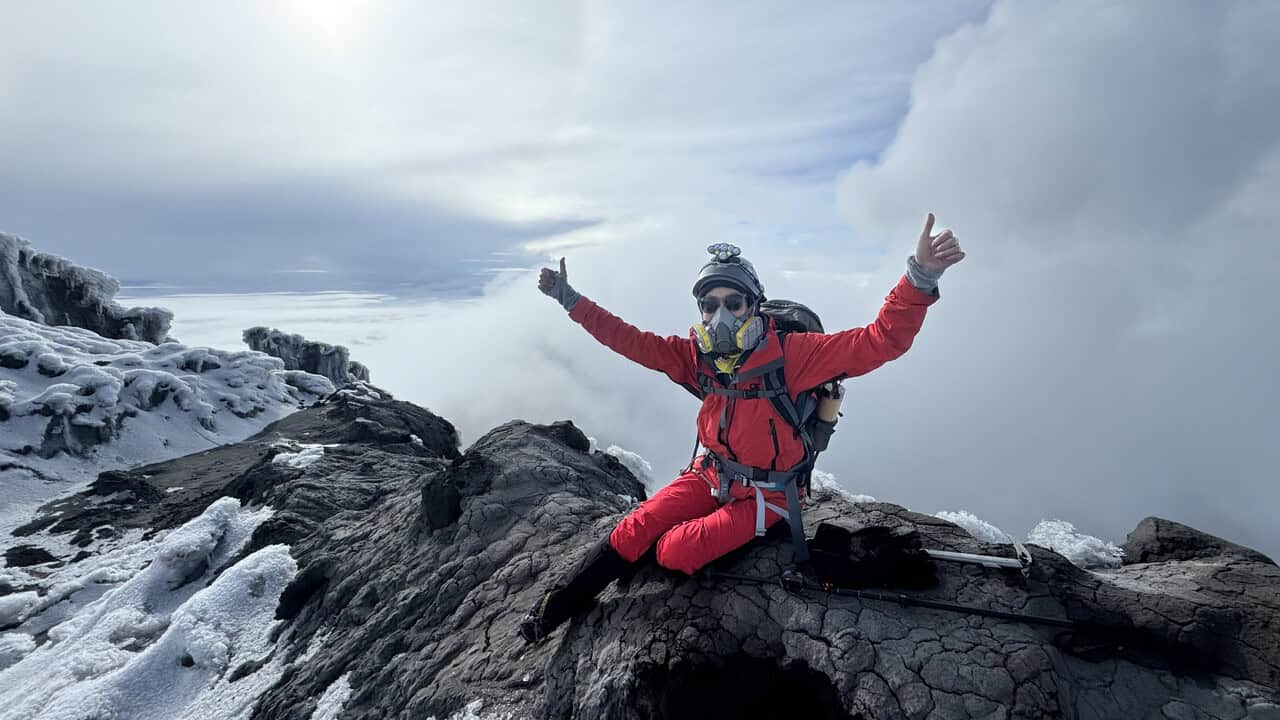 Woman on top of Mt Rainier with a gas mask on.