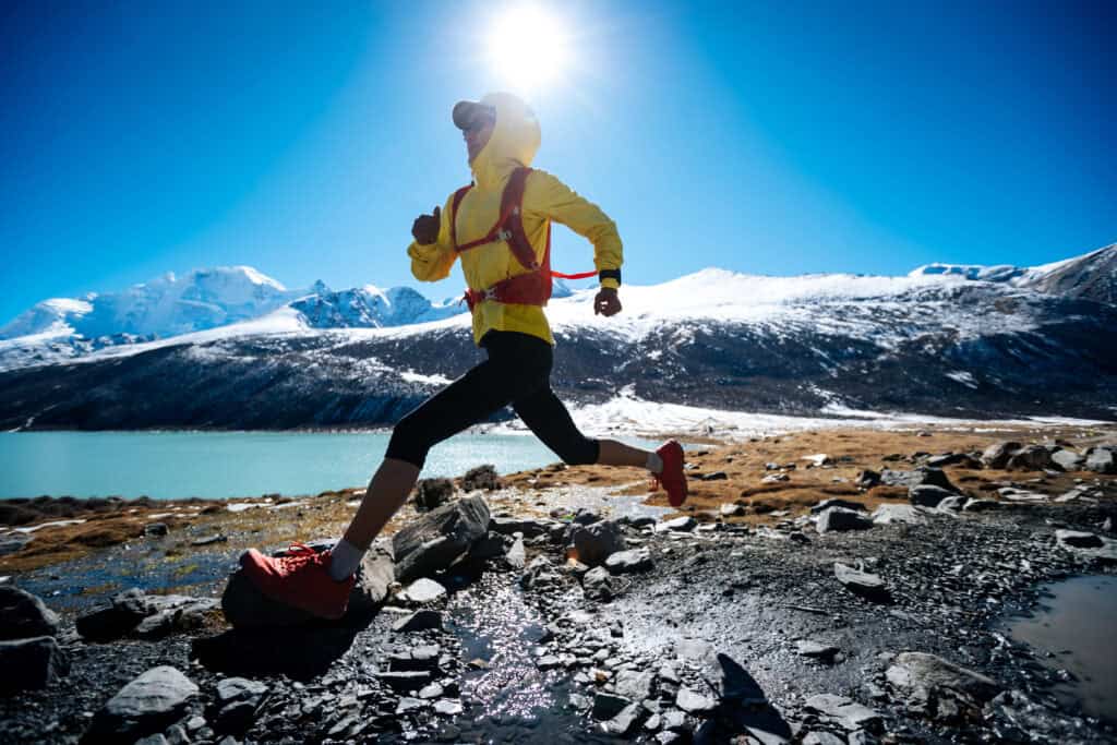 Woman in yellow jacket running at high altitude