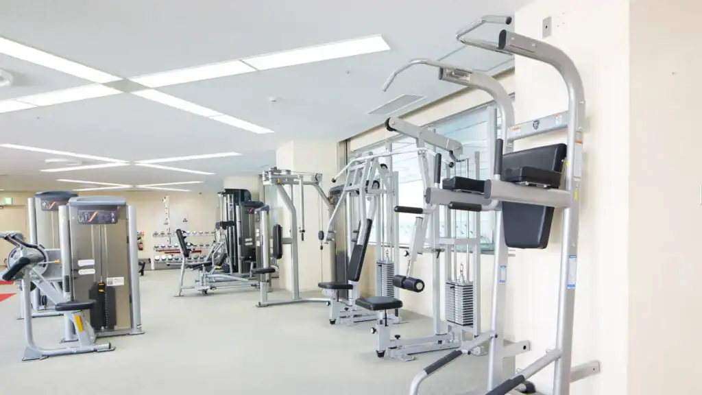 Modern basement gym with rubber flooring, mirrors, sauna, and home wellness space