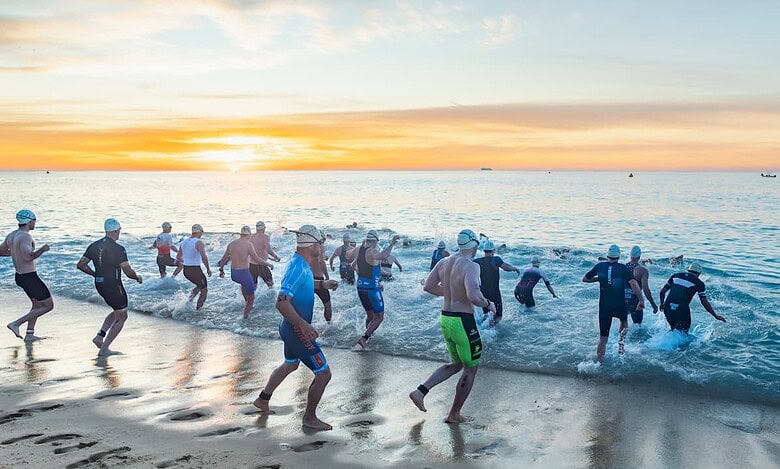 A group of athletes participating in an open water swim race at sunrise, demonstrating endurance and outdoor fitness.