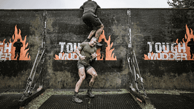 Participants navigating a challenging obstacle at Tough Mudder and Spartan Race UK, showcasing endurance and teamwork during the demanding event.