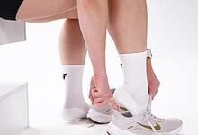 Close-up of a person tying running shoes while wearing Velocity Performance Crew Socks Adult (2 Pairs) for optimal athletic comfort.