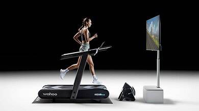 Woman running on a treadmill with virtual outdoor scenery on screen, showcasing indoor running and virtual training technology.